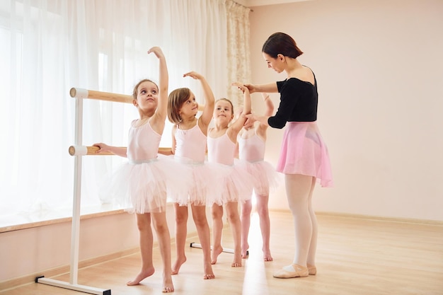 O treinador ensina as crianças Pequenas bailarinas se preparando para o desempenho praticando movimentos de dança