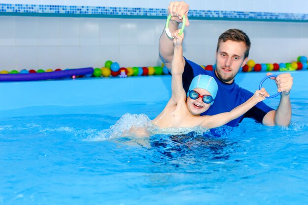 O treinador ensina o bebê a nadar na piscina.