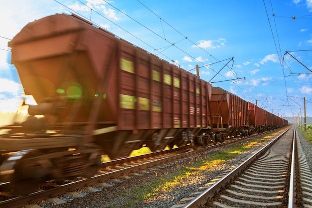 Foto o trem com vagões de carga se move por ferrovia em alta velocidade.