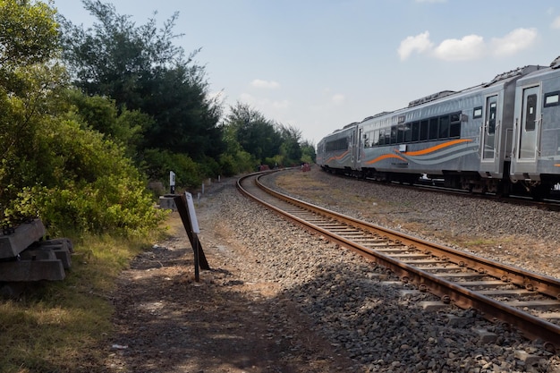 O trem doméstico passa pelo trilho durante o dia com céu azul