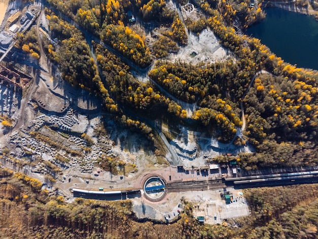 O trem é cercado por um desfiladeiro de lago de floresta de outono e pedreira de cima A vista do Parque Ruskeala do drone