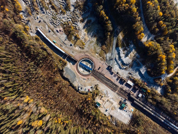 O trem é cercado por um desfiladeiro de lago de floresta de outono e pedreira de cima A vista do Parque Ruskeala do drone