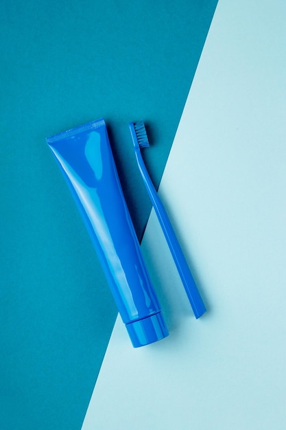 O tubo azul de pasta de dente e a escova de dente azul estão na vista superior do plano de fundo azul combinado