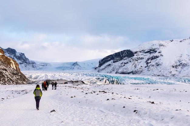 O turista dirige-se à geleira no panorama da geleira das montanhas islandesas