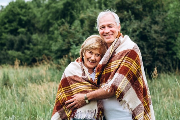 O velho casal caminha na natureza, dá as mãos, abraça