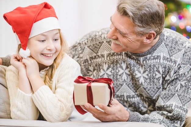 O velho dando uma caixa de presente para uma neta feliz