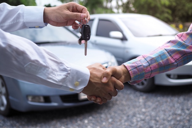 O vendedor de carros está entregando as chaves ao comprador após o contrato ter sido acordado.