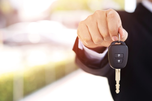 O vendedor está entregando as chaves do carro novo ao cliente no showroom.