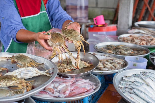 O vendedor local de frutos do mar espera e mostra duas garras. Loja de frutos do mar local na Tailândia.