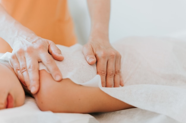 Foto o verdadeiro médico osteopata faz terapia fisiológica e emocional para uma menina de oito anos. sessão de tratamento de osteopatia pediátrica. medicina alternativa. cuidando da saúde da criança