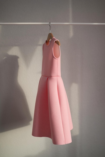 O vestido rosa está pendurado em um cabide Roupas infantis