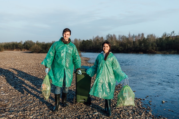 O voluntário do homem com menina tira o lixo na praia. poluição ambiental do litoral, lixo e lixo ao ar livre.