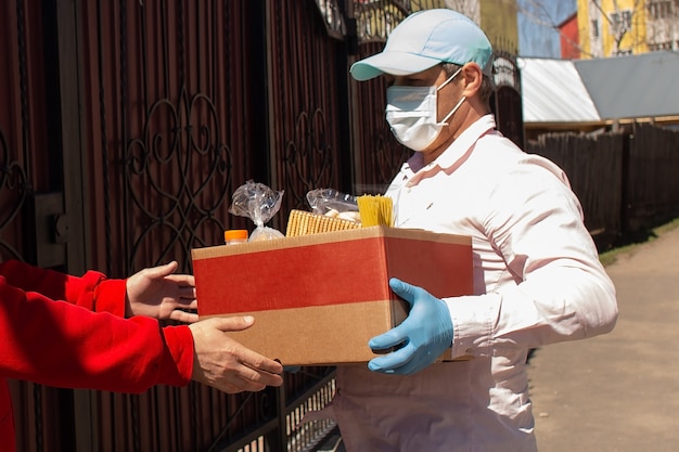 O voluntário entrega uma caixa de comida para quem precisa
