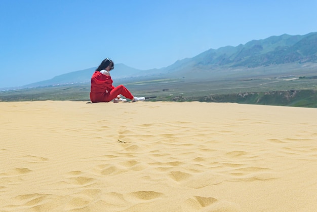 Oben auf der Sarykum-Sanddüne in Dagestan eine Eidechse im Sand und eine unscharfe Touristin im Hintergrund