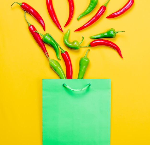 Oben Blick auf Chili-Pfeffer und Einkaufstasche auf gelbem Hintergrund
