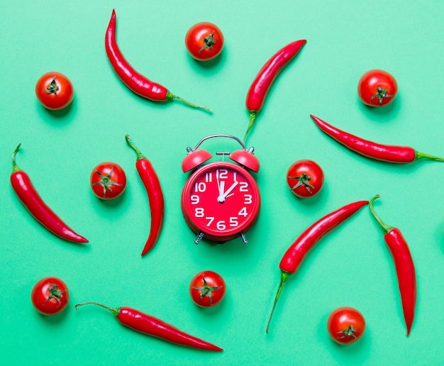 Oben Blick auf Chili-Pfeffer und Wecker mit Tomaten auf gelbem Hintergrund