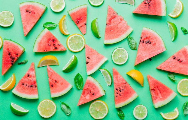 Oben Blick auf geschnittene Zitronen und Limetten mit Wassermelone auf grünem Hintergrund