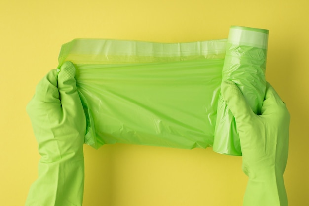 Oben POV-Foto von Müllsack und grünen Handschuhen isoliert auf gelbem Hintergrund