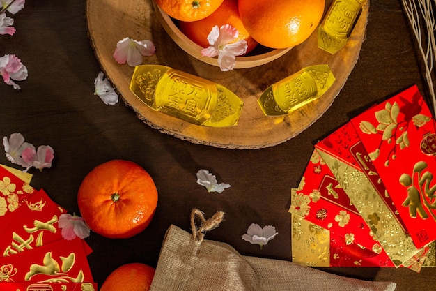 Oben sehen Sie Accessoires des chinesischen Neujahrsfests oder des Mood Day-Festivals in Orangengold und Angpao-Taschen mit Kirschblüten-Zweigdekorationen.