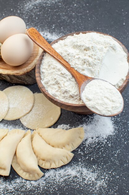 Oben sehen Sie rohe Kartoffel-Hotcakes mit Eiern und Mehl auf dunklem Hintergrund Kuchenteig, der Keks-Ofen-Kuchen-Essen backen