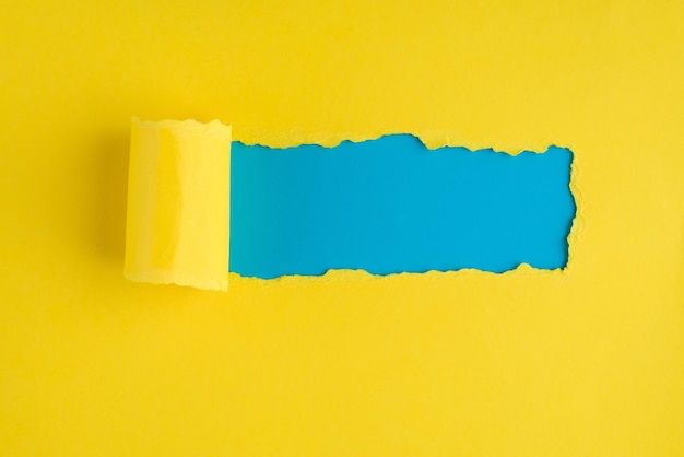 Oben über der Draufsicht Foto von zerrissenem gelbem Papier über blauem Hintergrund mit Exemplar