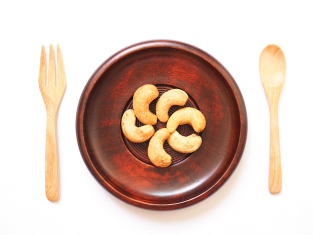 oben von der Diätnahrung, sauberes Essen mit Acajounüssen auf hölzerner Platte, Teller, Löffel und Gabel von natürlichem für gute Gesundheit