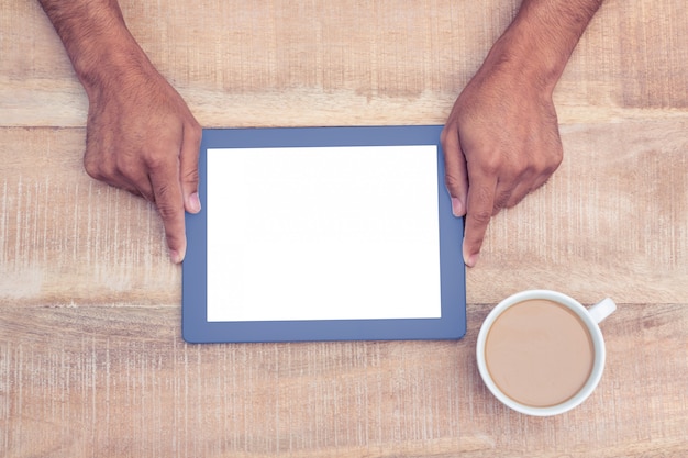 Obenliegende Ansicht der Hand digitale Tablette über Tabelle durch Kaffee an halten