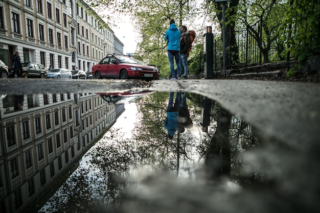 Foto oberflächenebene der pfütze mit reflexion von gebäuden und menschen in der stadt während des monsuns