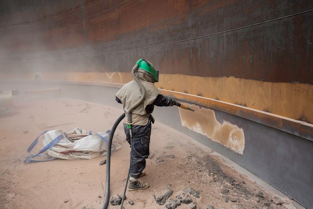 Oberflächenkorrosionsplattenvorbereitung der Arbeiterin durch Sandstrahlen des Öls im Inneren des Tanks