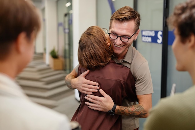 Oberkörperporträt junger Geschäftsleute, die sich umarmen, während sie die Beförderung im Amt feiern