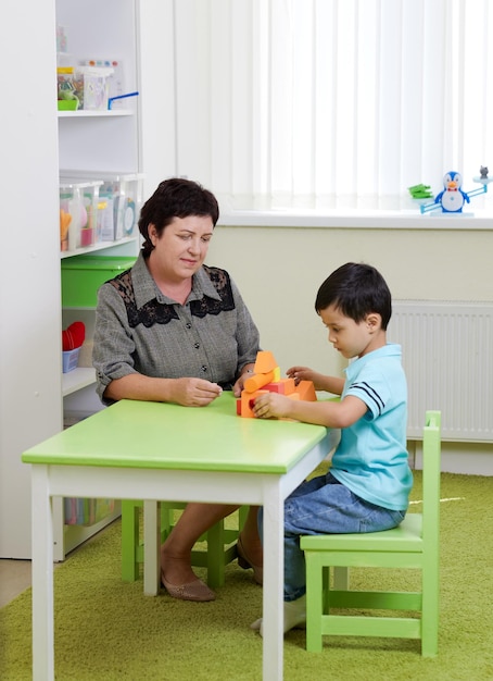 Oberlehrer und Vorschulkind spielen im Spielzimmer