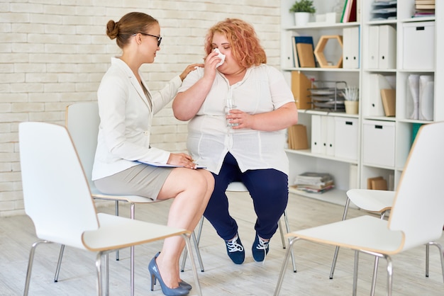 Obesa joven llorando en reunión con psiquiatra