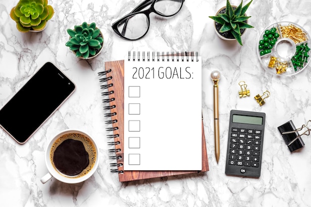Objetivo de año nuevo 2021, plan, texto de acción en el bloc de notas abierto, vasos, taza de café, bolígrafo, teléfono inteligente
