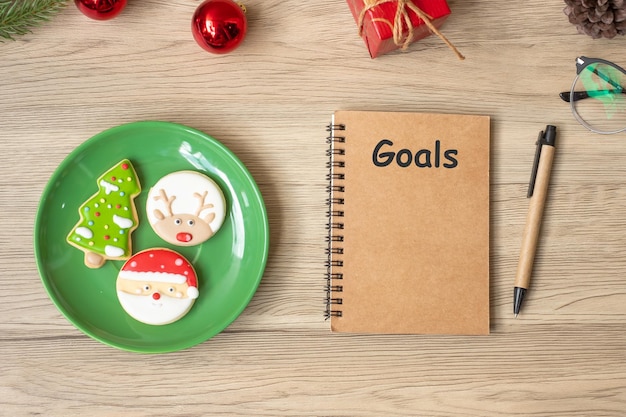 OBJETIVO con cuaderno negro Galletas de Navidad y bolígrafo sobre mesa de madera Vista superior y espacio de copia Navidad Feliz año nuevo Resolución Lista de tareas Concepto de estrategia y plan