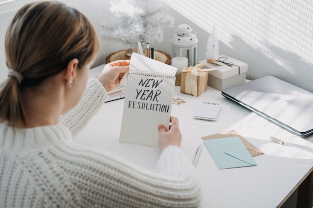 objetivos resolução de ano novo mulher em suéter branco escrevendo texto resolução de ano novo em bloco de notas aberto