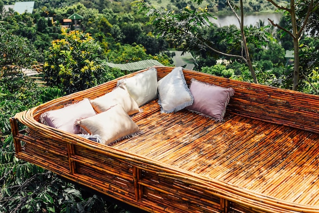 Objetos creativos en cama de madera de Vietnam con almohadas acogedoras contra el paisaje vietnamita de la ciudad de Da Lat