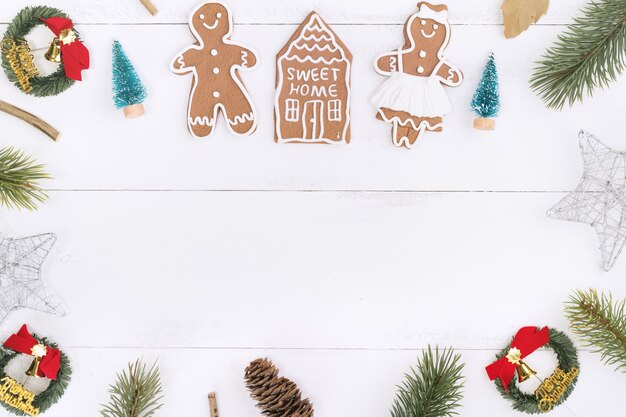 Objetos de decoração de composição de conceito de Natal, grinalda de galho de árvore de abeto, biscoito de homem-biscoito isolado na mesa de madeira branca, vista superior, postura plana