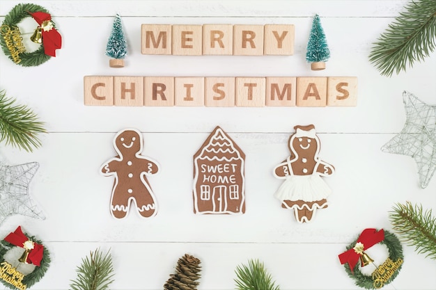 Objetos de decoración de composición de concepto de Navidad, corona de rama de abeto, galleta de hombre de jengibre aislado en mesa de madera blanca, vista superior, endecha plana