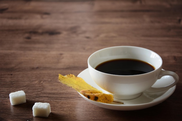 Objetos en una mesa de madera, una taza de café y un libro.