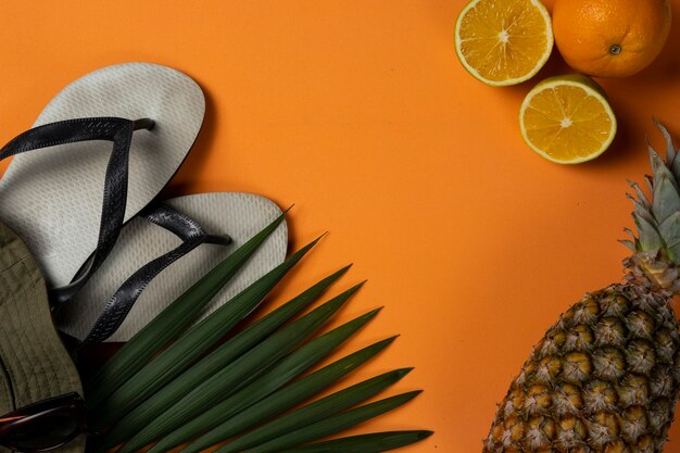 Objetos de playa y frutas sobre fondo de playa de verano naranja