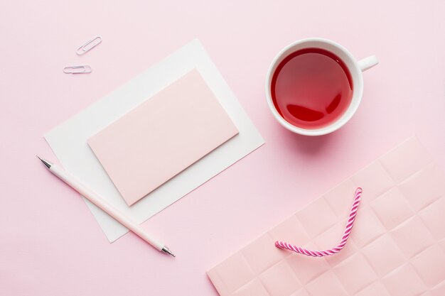 Objetos rojo-rosa. Taza de té y libreta para el texto en fondo del rosa en colores pastel.