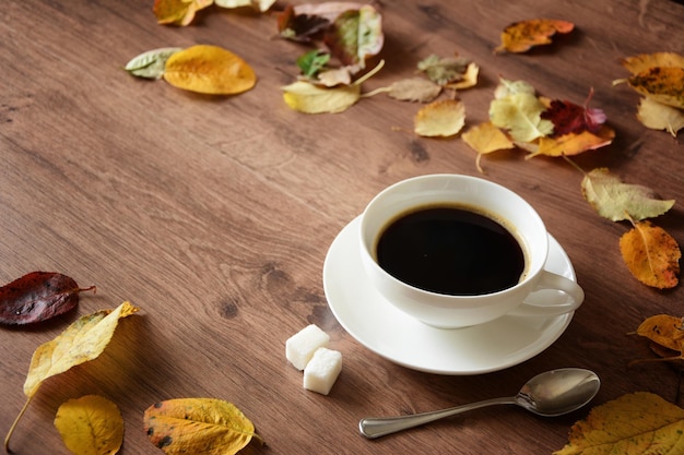 Objetos sobre uma mesa de madeira, uma xícara de café e um livro