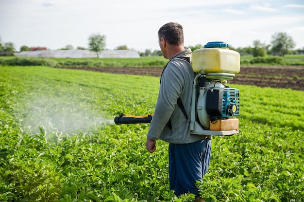 Oblast de Kherson Ucrania 22 de mayo de 2021 Un agricultor rocia una plantación de patatas con un pulverizador Protección efectiva de las plantas cultivadas contra insectos y hongos Pulverizador de niebla pesticida fungicida