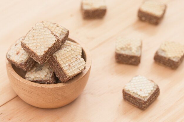 Obleas con chocolate en taza sobre fondo de madera.