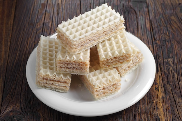 Obleas en plato blanco sobre mesa de madera oscura.