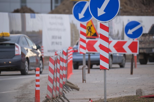 Obras viales que advierten señales de tráfico de trabajos de construcción en las calles de la ciudad y automóviles que se mueven lentamente