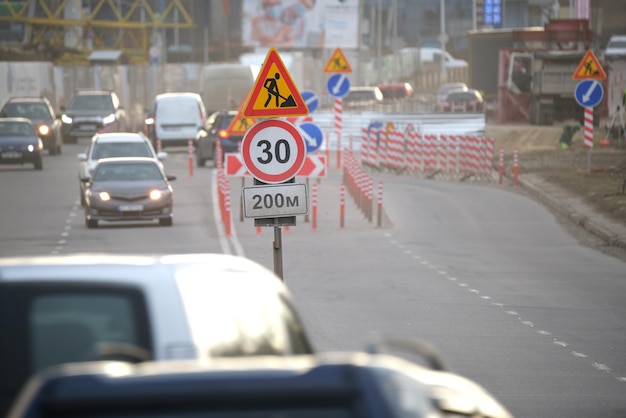 Obras viales que advierten señales de tráfico de trabajos de construcción en las calles de la ciudad y automóviles que se mueven lentamente