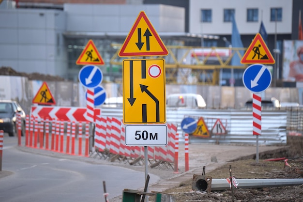 Obras viales que advierten señales de tráfico de trabajos de construcción en las calles de la ciudad y automóviles que se mueven lentamente