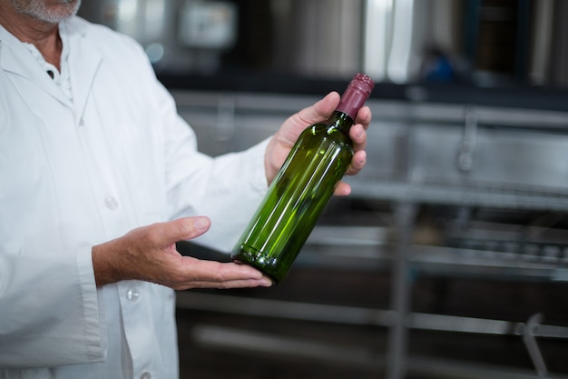 Obrero examinando una botella en fábrica