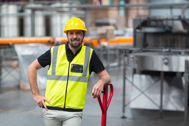 Obrero de pie con la mano en la cadera en fábrica